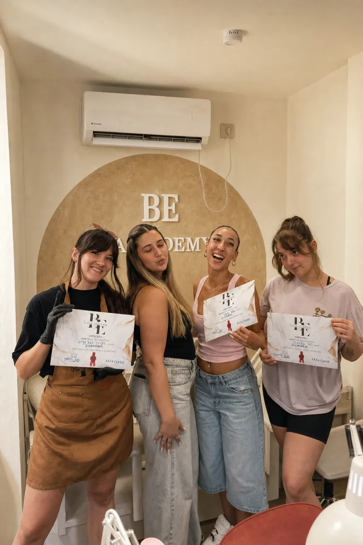 ארבע בוגרות עומדות עם תעודות הסיום שלהן מול קיר הקשת